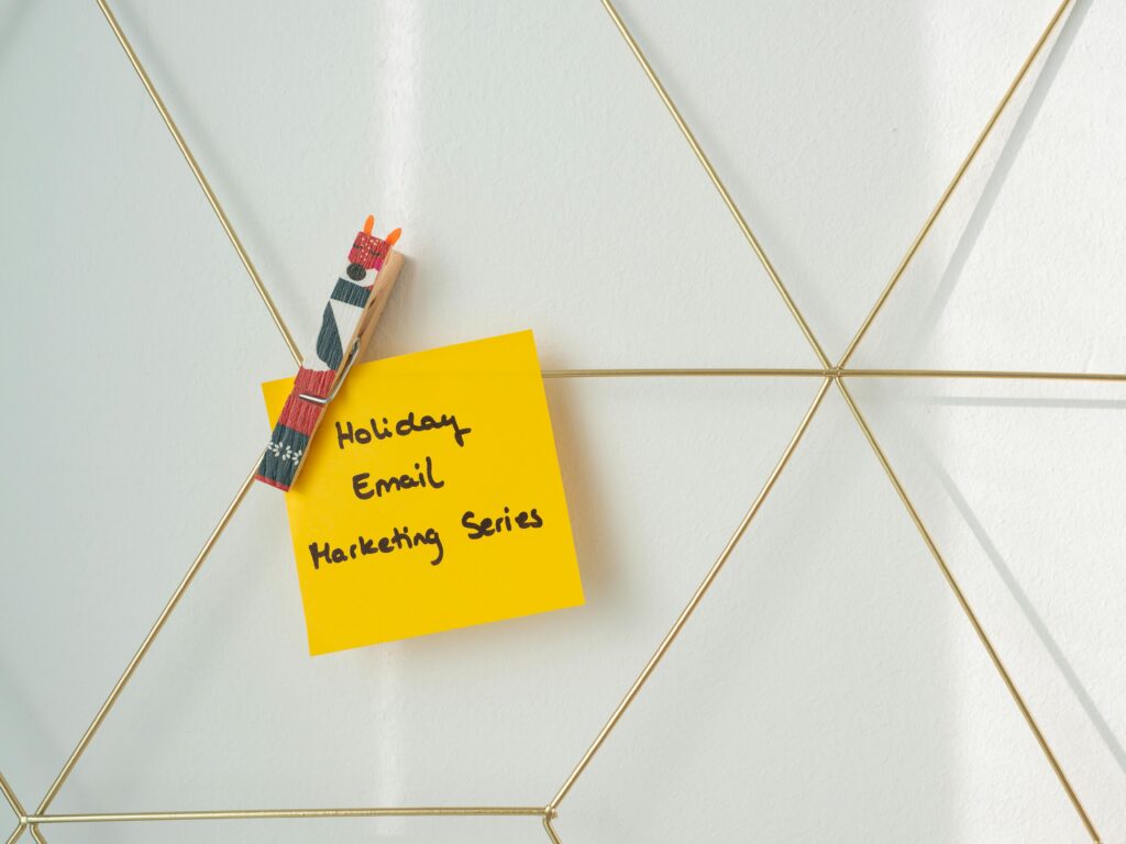 Bright yellow sticky note with holiday email marketing message clipped to a wireframe wall.